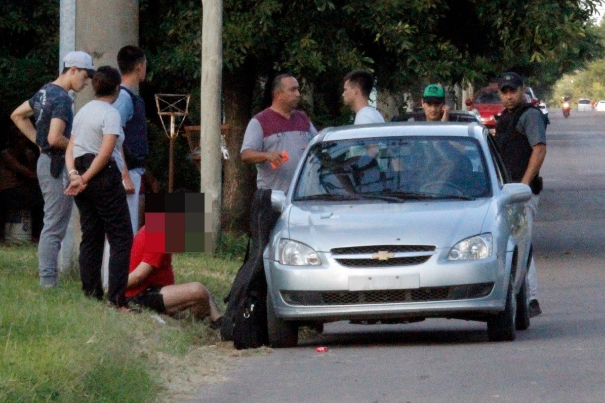 La persona demorada sentada rodeada de personal policial de civil