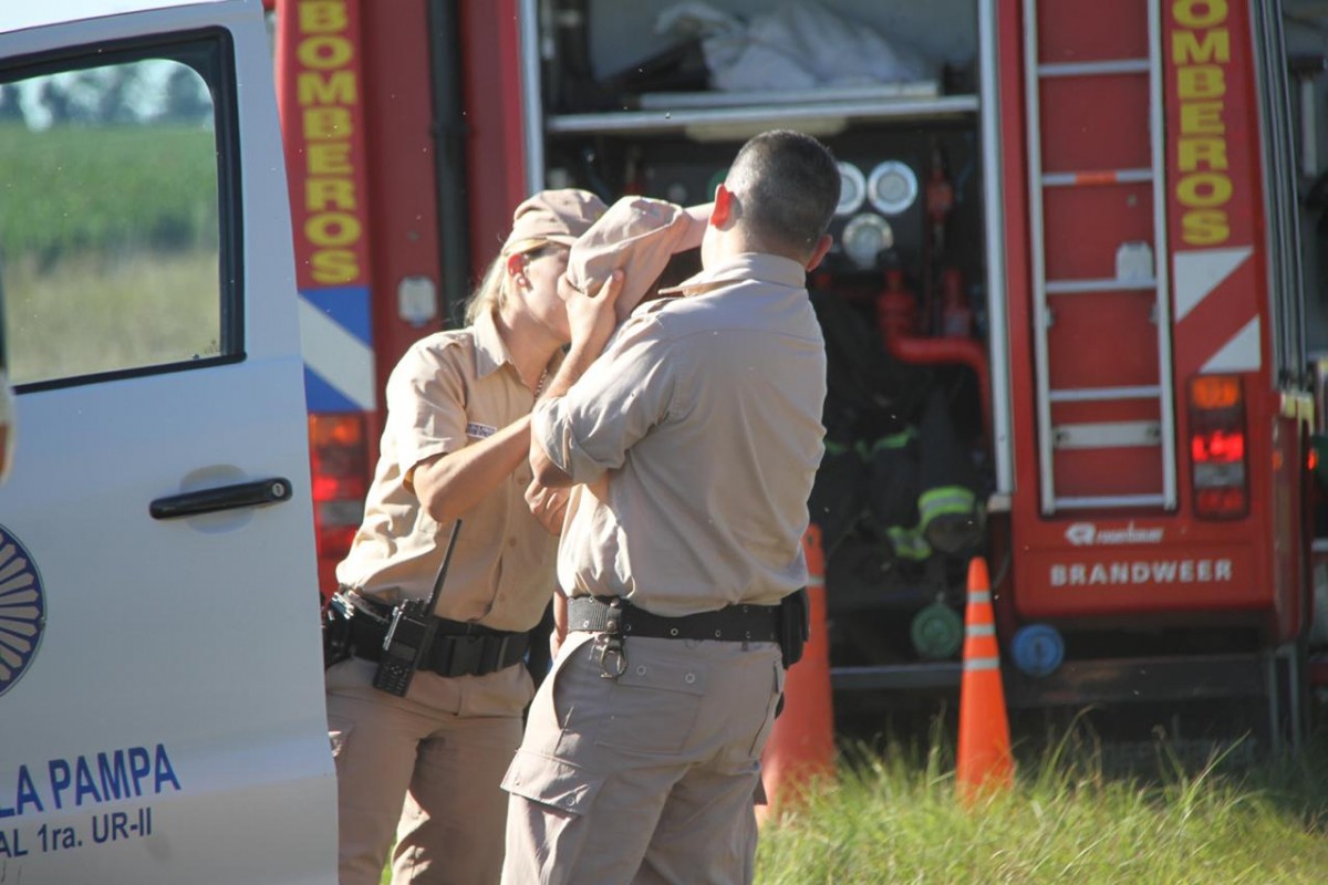 El policía con el bebé en brazos, mientras lo protege con su gorra del sol. El policía con el bebé en brazos, mientras lo protege con su gorra del sol.