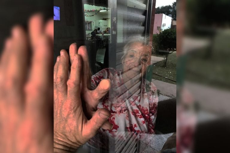 Tierna y cruda imagen de una realidad: un nieto y su abuela se saludan a través del vidrio en una localidad pampeana