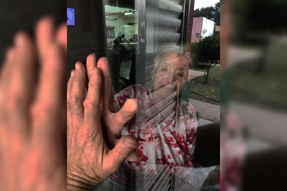Tierna y cruda imagen de una realidad: un nieto y su abuela se saludan a través del vidrio en una localidad pampeana