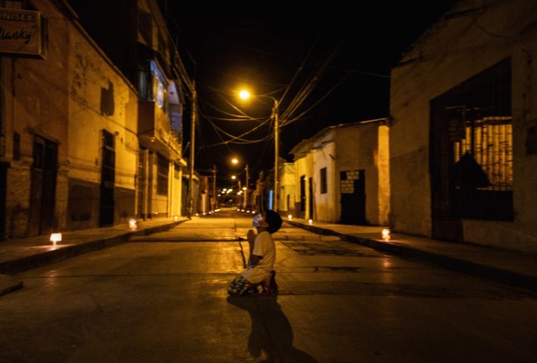 Un niño se arrodilla a rezar en la calle para que se termine la pandemia por coronavirus en Perú