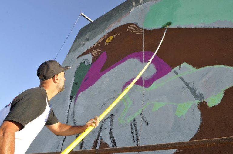 Un artista se encuentra renovando un mural en homenaje a la lucha por los ríos pampeanos