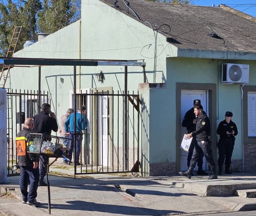Agentes de policía y personal de defensa civil realizan un operativo frente a una vivienda