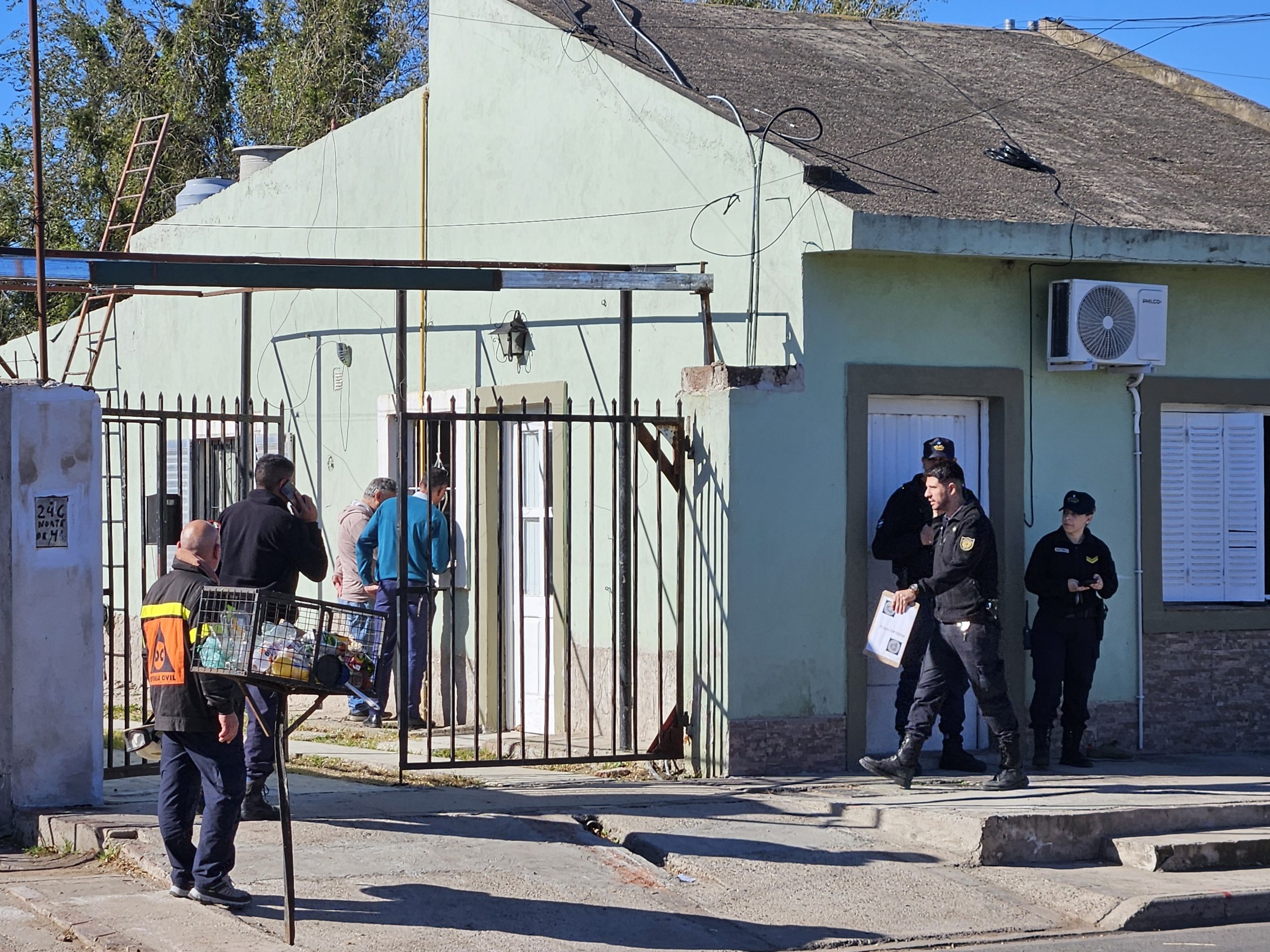 Agentes de policía y personal de defensa civil realizan un operativo frente a una vivienda